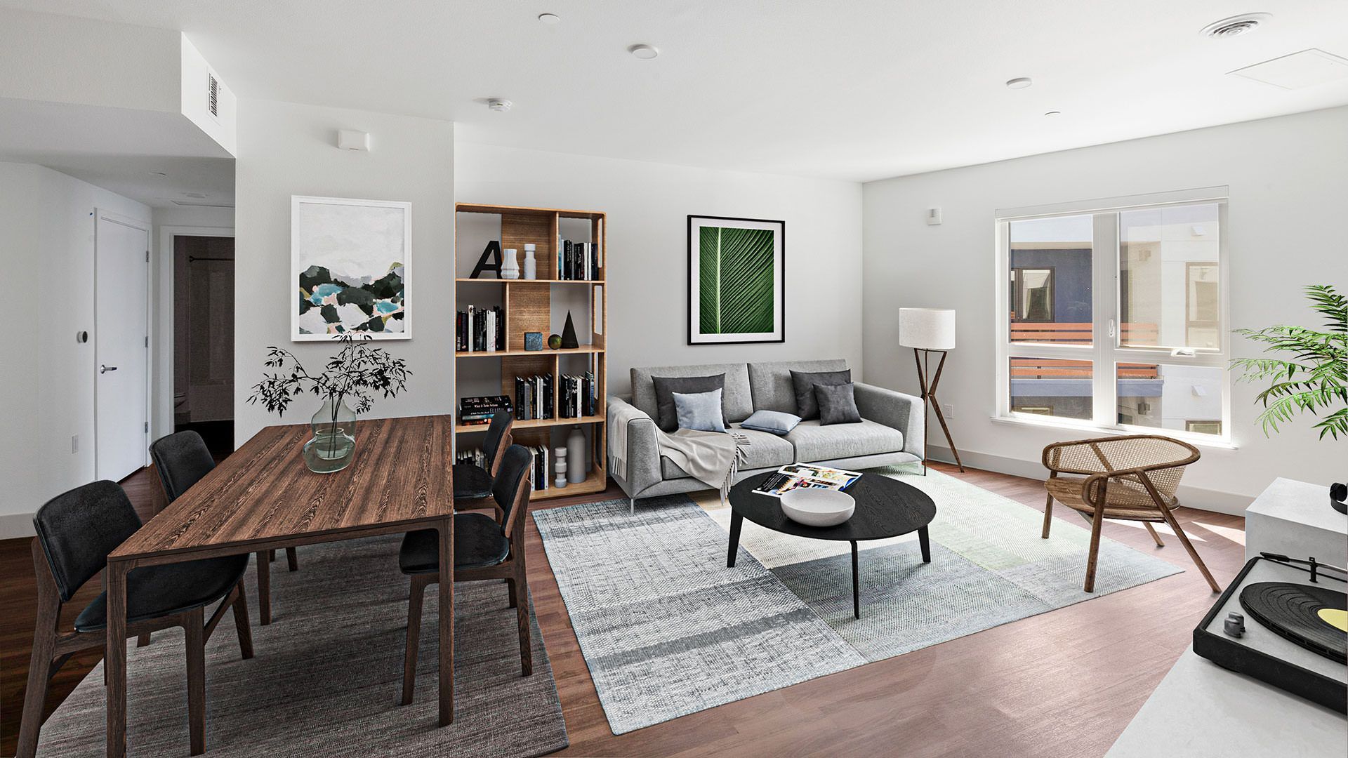 Modern living room with dining area, bookshelves, sofa, and coffee table. Light wood floors, white walls, and natural light at The Waymark in Walnut Creek, CA.