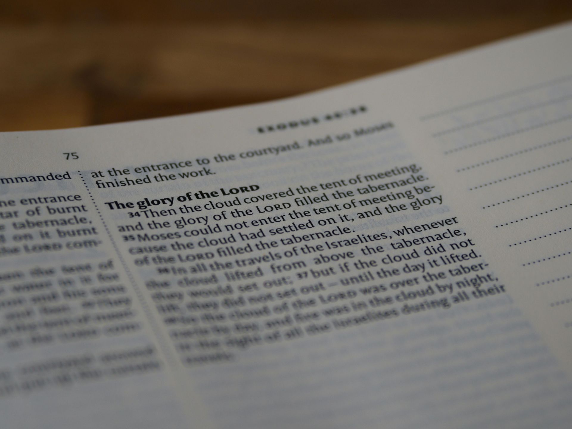 A close-up, angled view of an open Bible page showing the text of Exodus 40:34-38, with lined space for notes to the right.