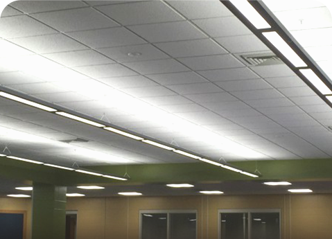 A drop ceiling with grid tiles, linear fluorescent lights, and rectangular HVAC vents above a room with green accents.