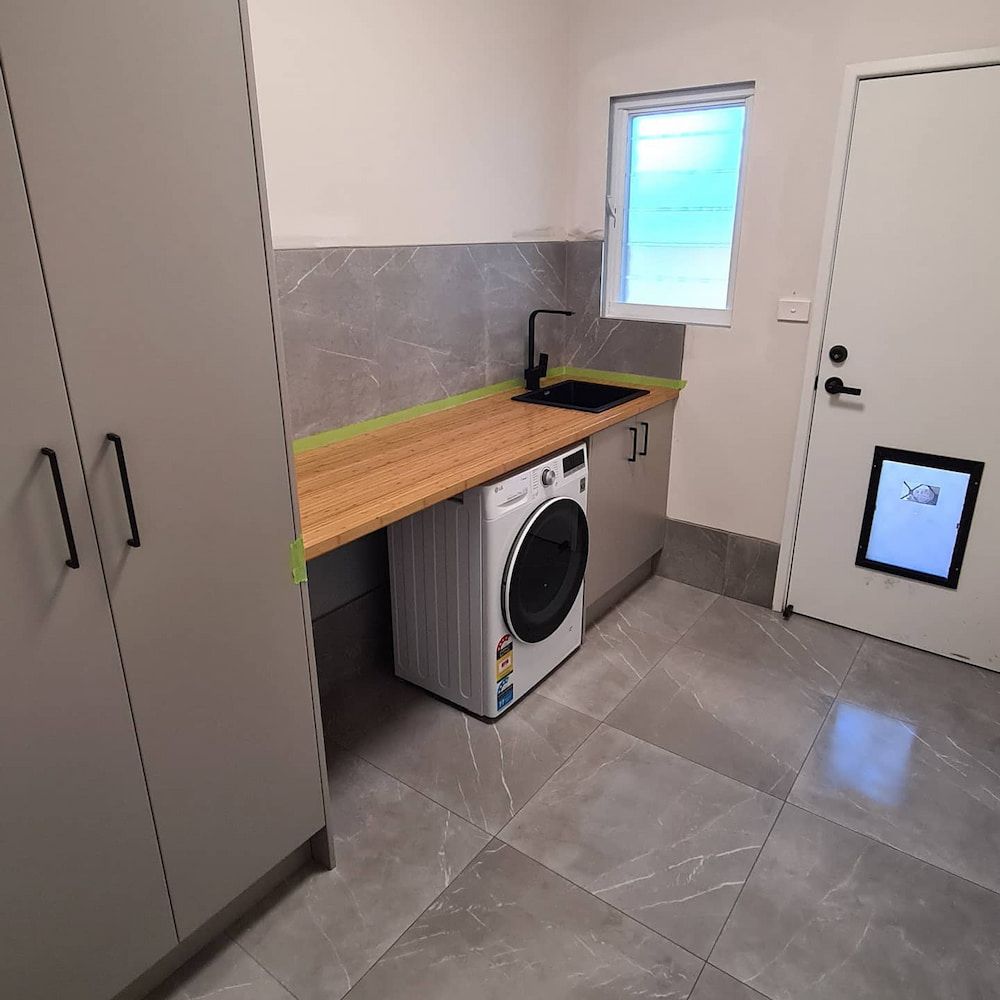 A Laundry Room With A Washer And Dryer And A Sink — The Kitchen & Bathroom Doctor in Medowie, NSW