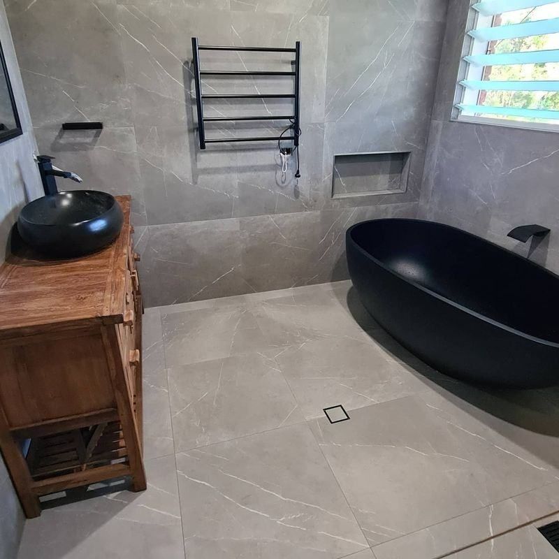 A Bathroom With A Black Bathtub , Sink And Mirror — The Kitchen & Bathroom Doctor in Medowie, NSW