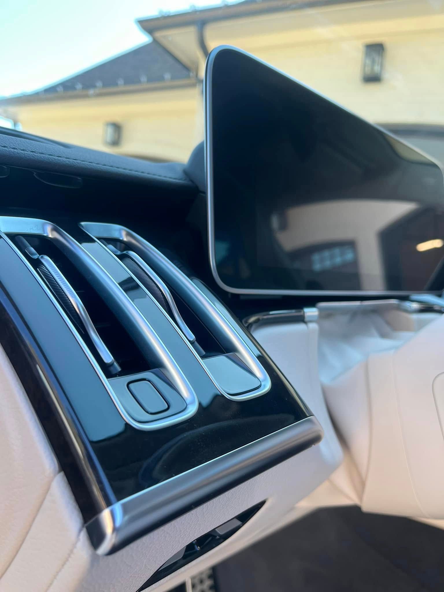 Close-up of a glossy car center console with silver control sliders and an open touchscreen display