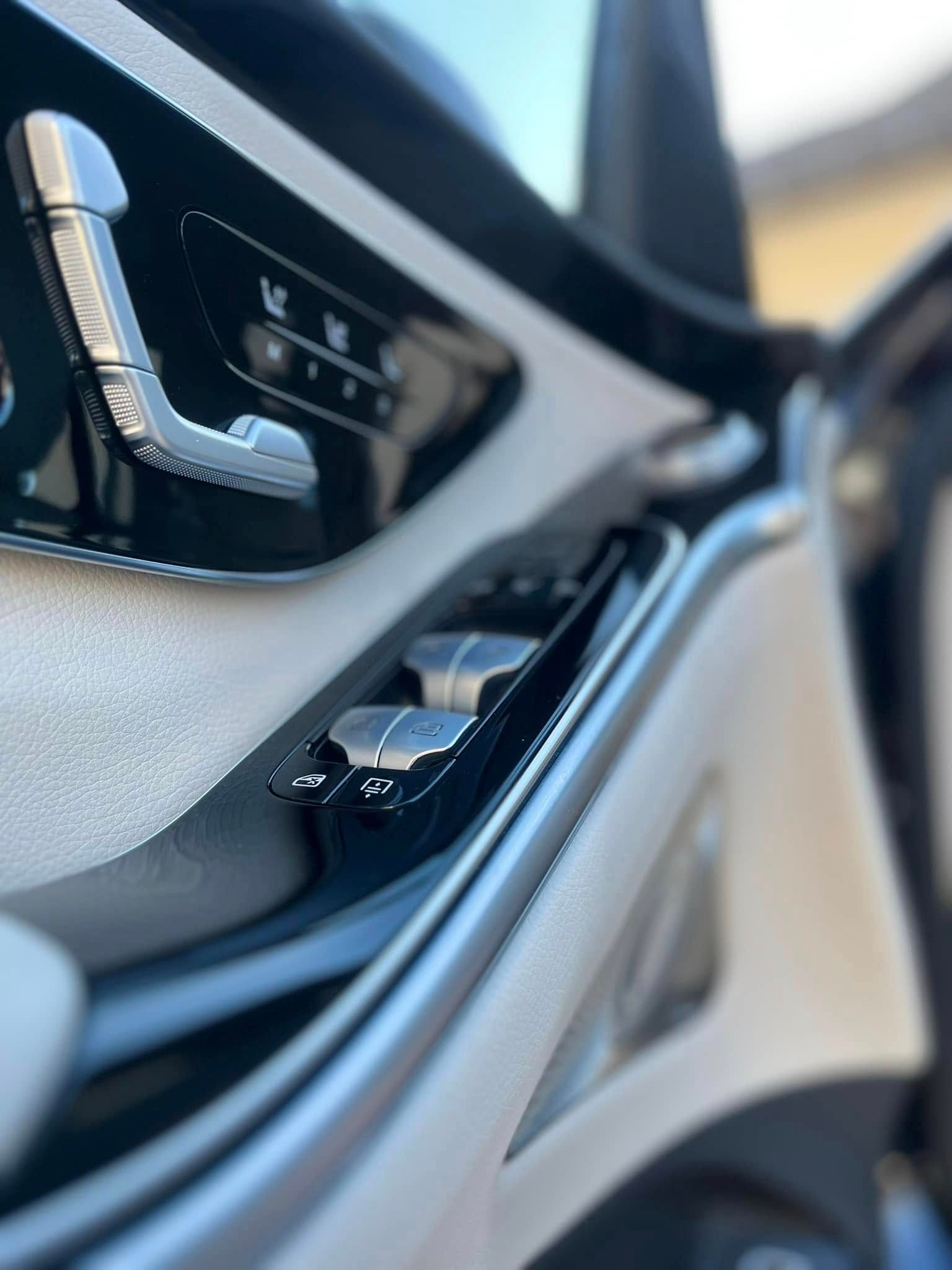 Close-up of a car’s black door controls with chrome accents and a window switch.