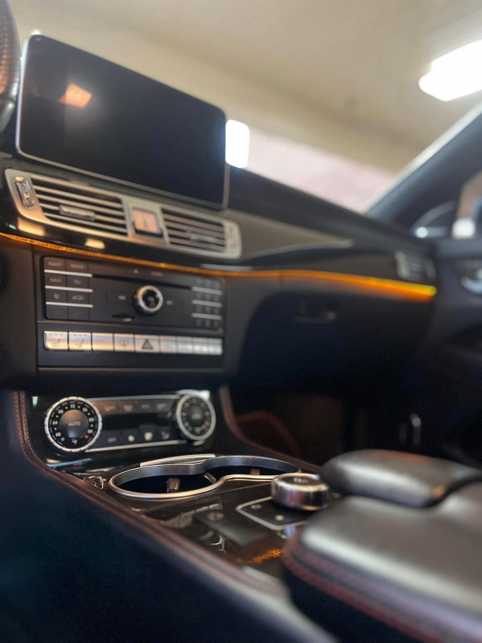 Luxury car interior with dashboard screen, wood trim, and center console.