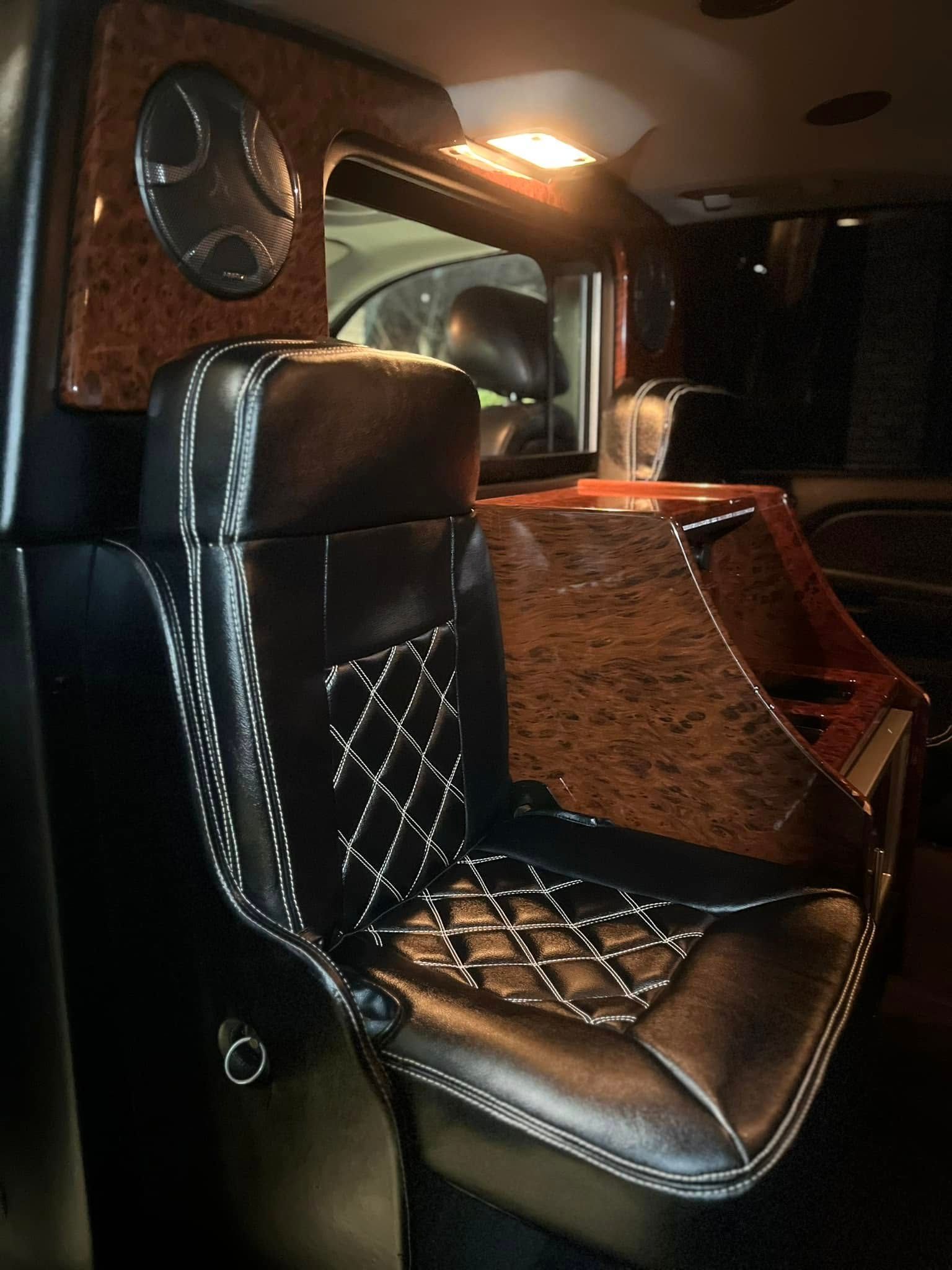 Black leather captain’s chair in a dimly lit luxury vehicle interior with wood accents and quilted stitching