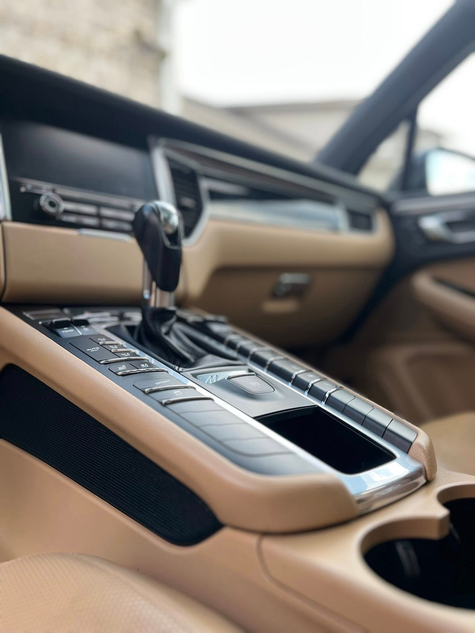 Tan leather car interior with a center console, gear shift, and cup holder