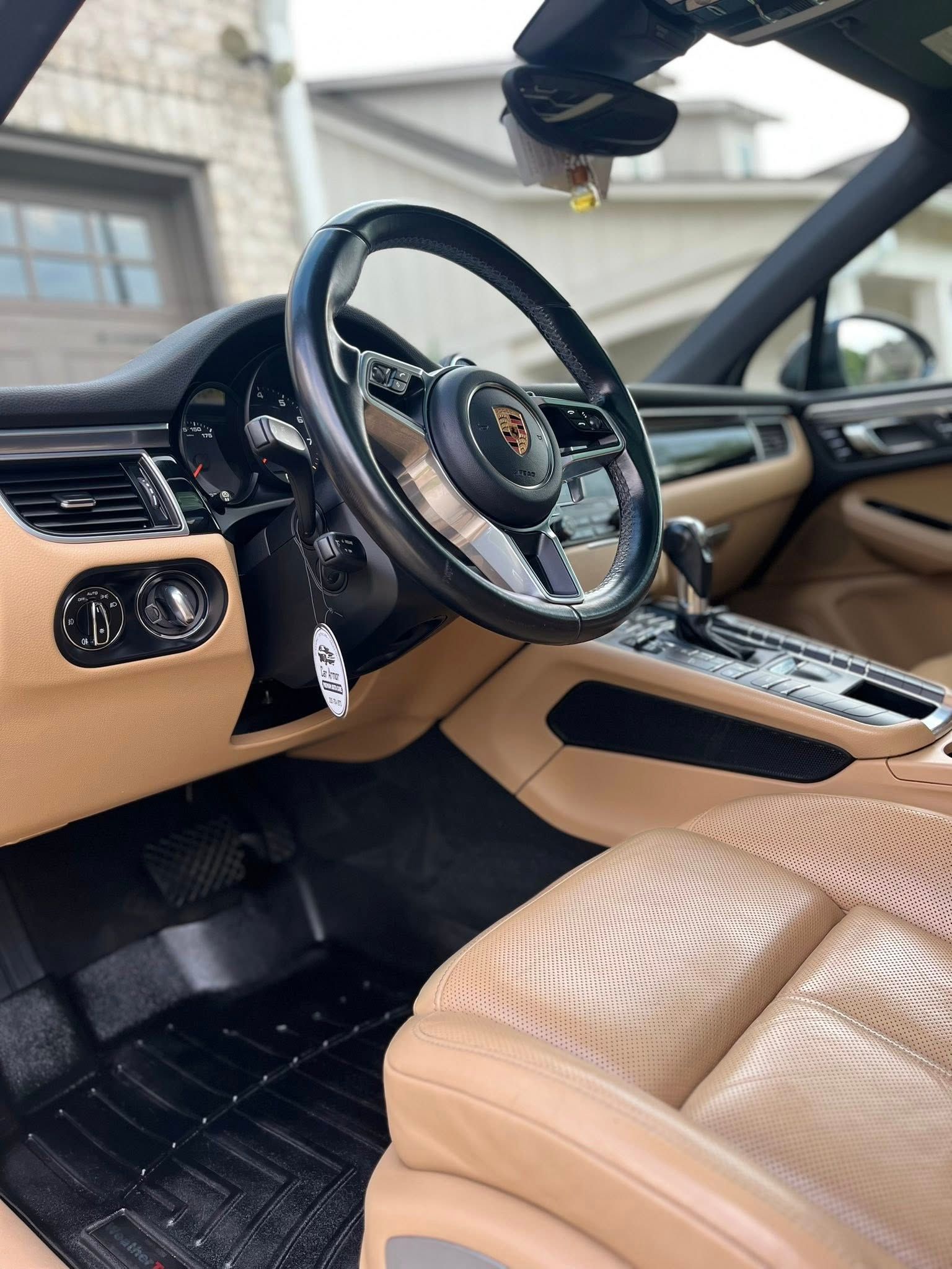 Luxury car interior with tan leather seats, black dashboard, and detached steering wheel in a damaged cabin