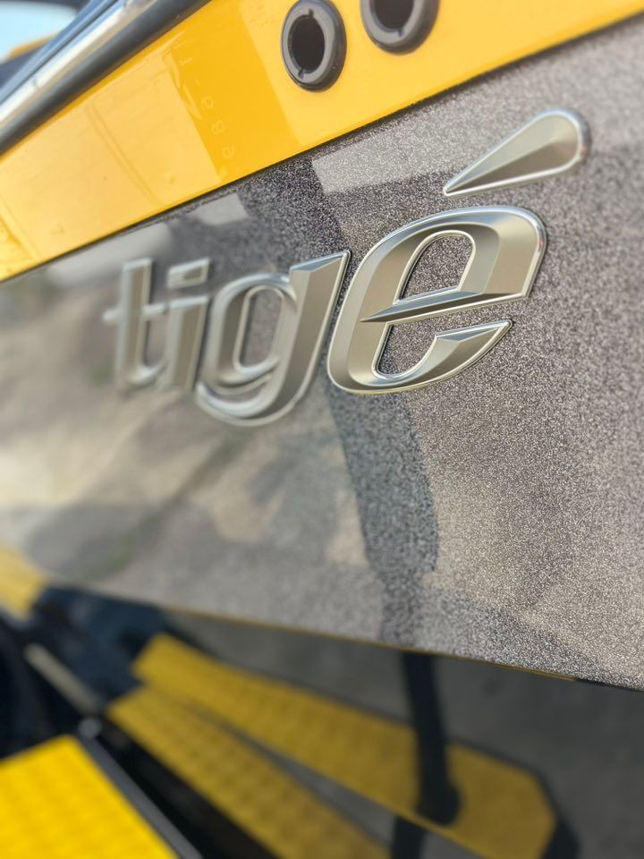 Close-up of a gray and yellow boat hull with the word “tige” logo.