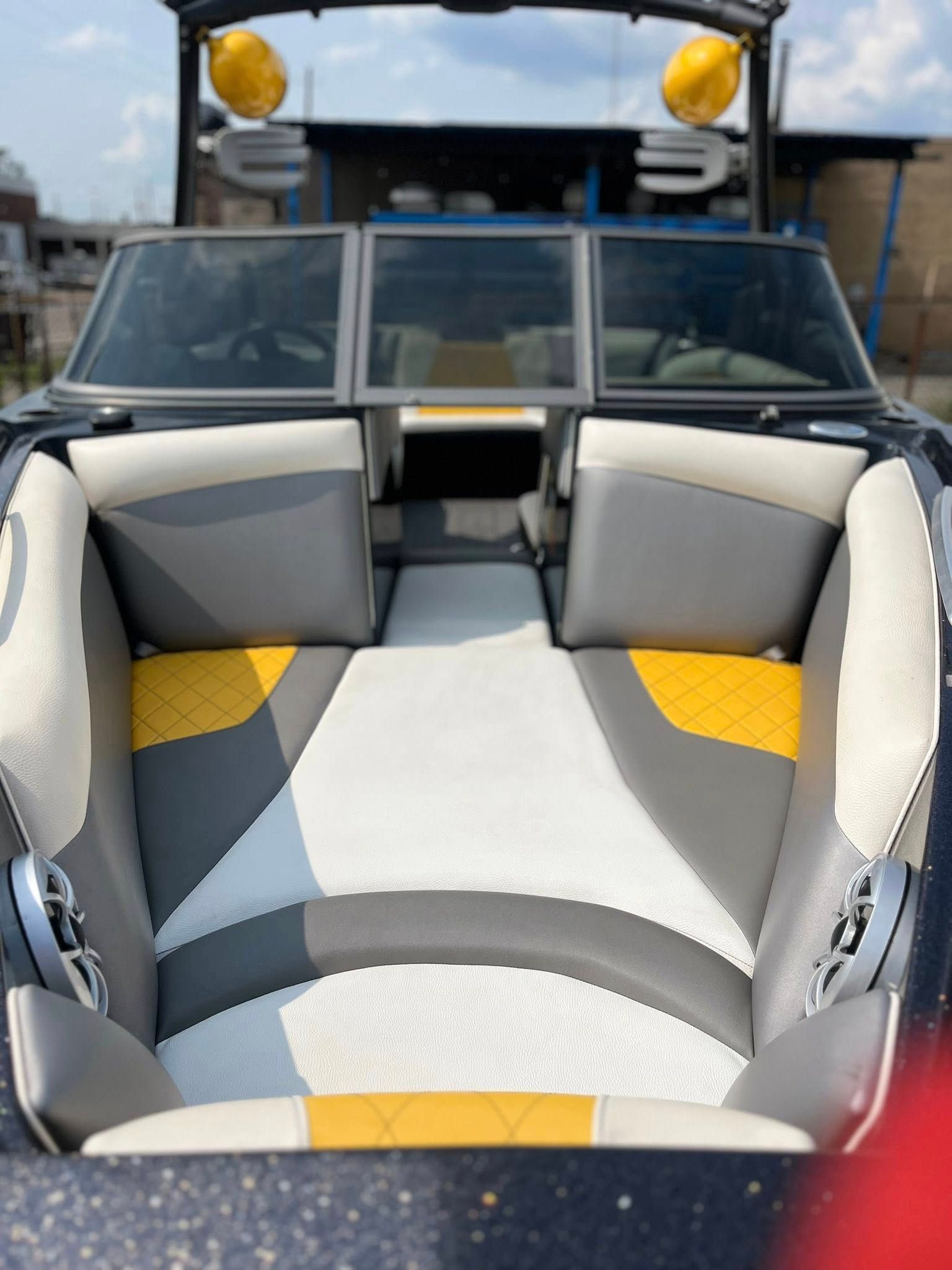Empty gray-and-yellow upholstered boat seats viewed from the stern toward the helm