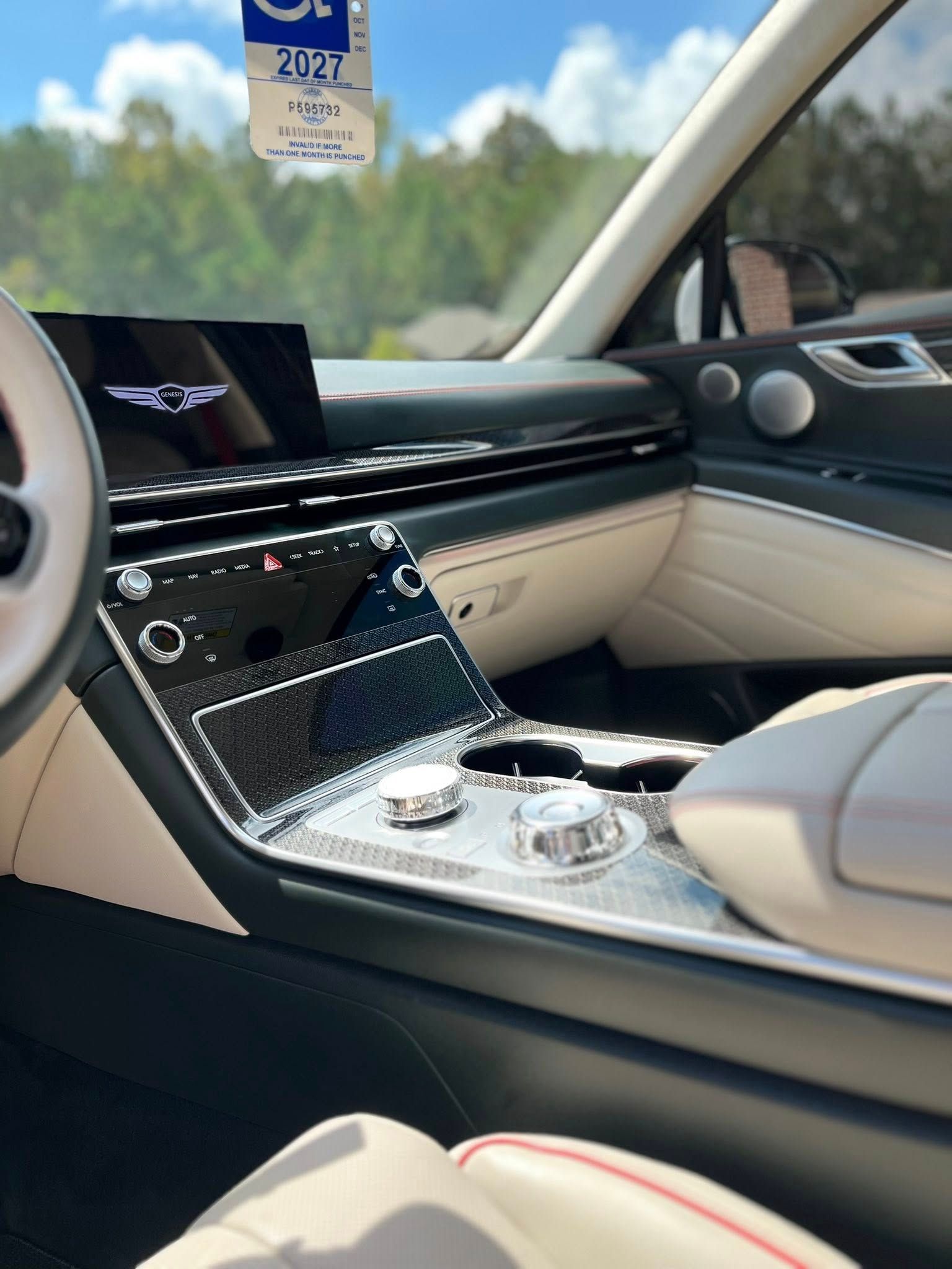 Luxury car interior with cream and black leather, diamond-pattern console, and cupholders by the window