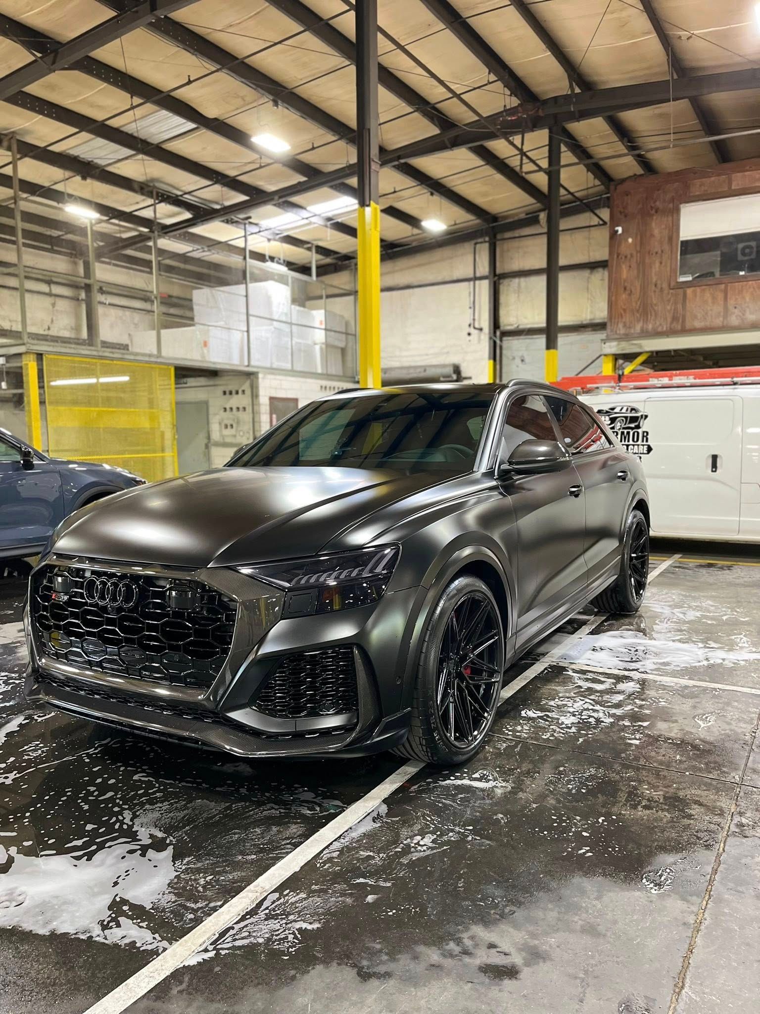 Black SUV parked in an indoor garage, covered in water and snow with a yellow post nearby