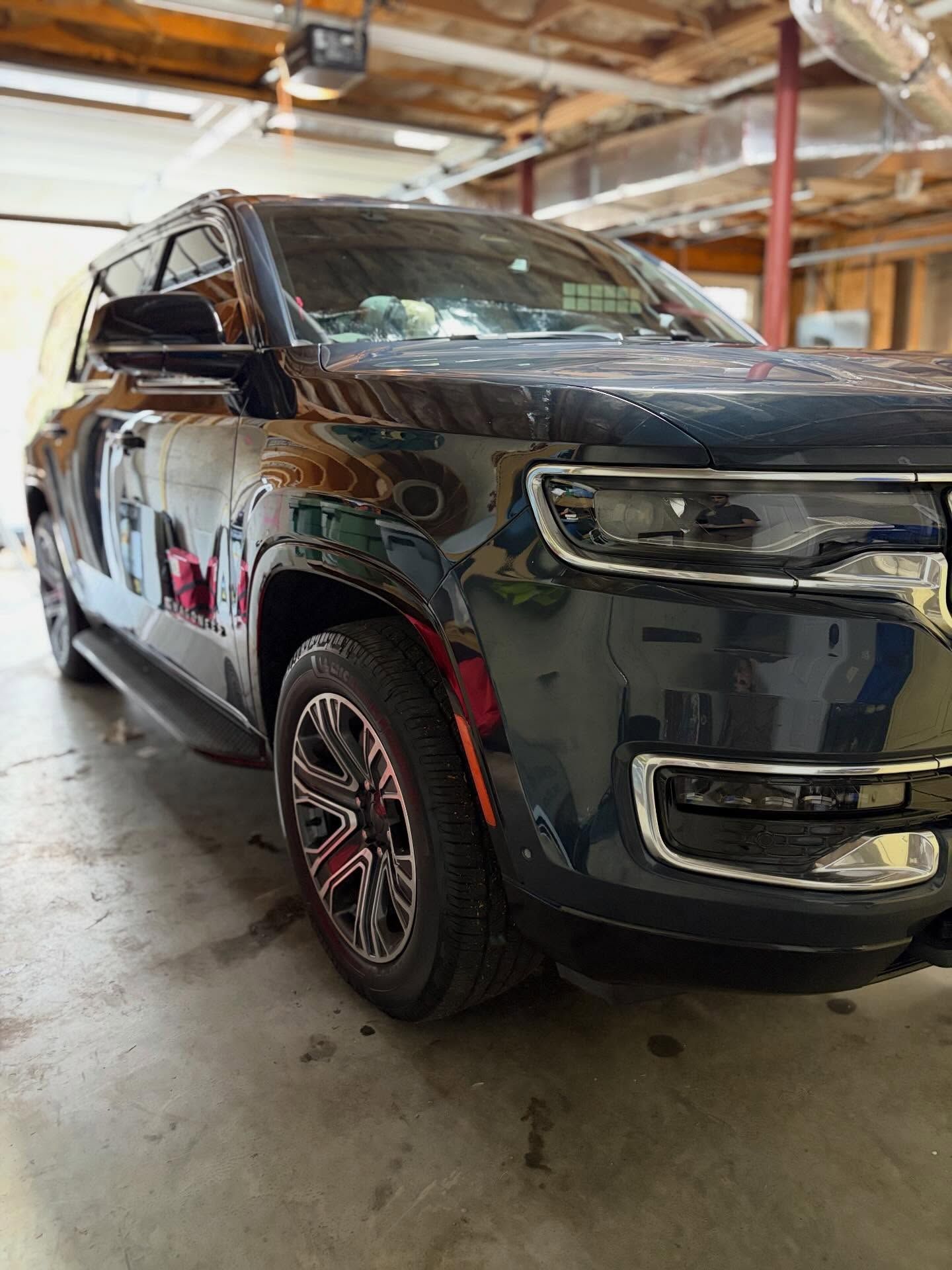 Black SUV parked inside a garage, front-left view on a concrete floor