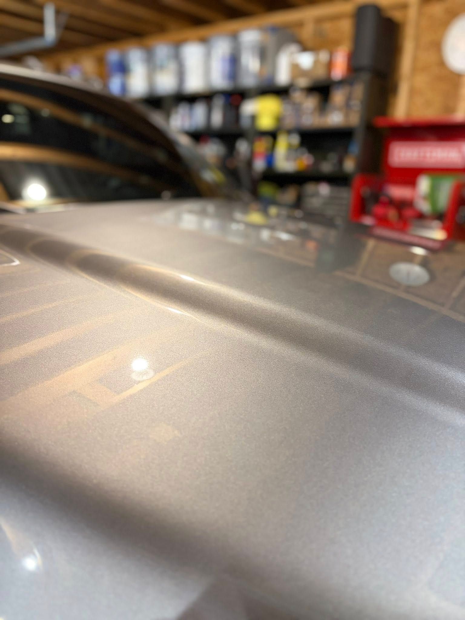 Silver car hood with visible scratches in a garage