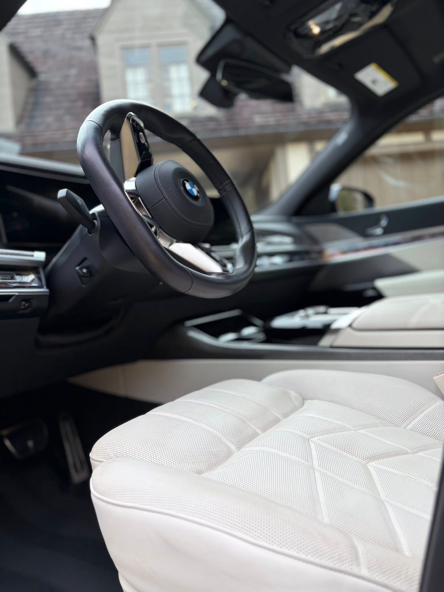 Luxury car interior with white embroidered seats and black dashboard, viewed from the driver's side
