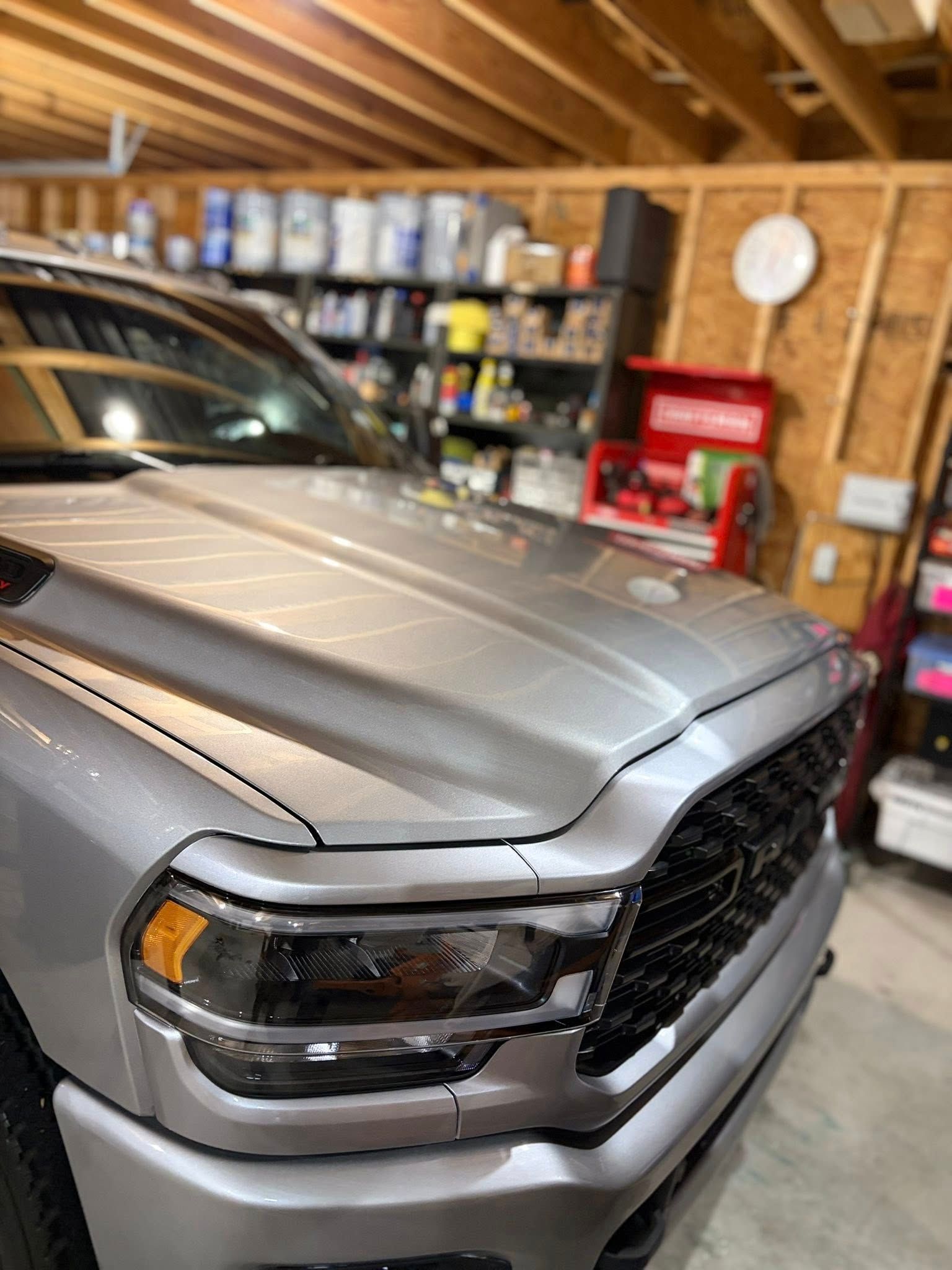 Silver pickup truck in a garage, front end close-up with black grille and headlights.