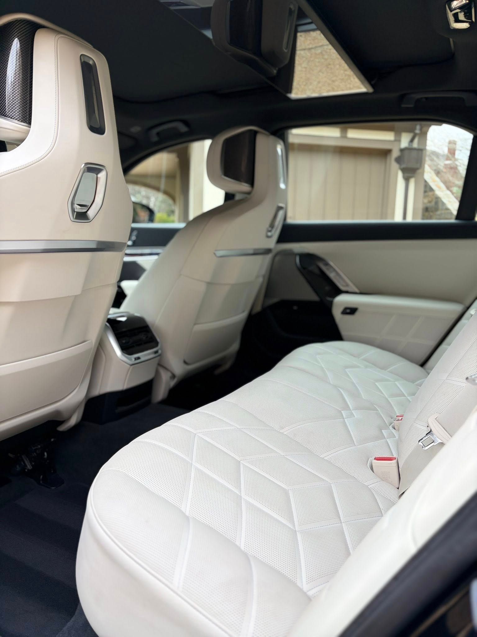 White luxury car interior with quilted rear seat and cream leather front seats, viewed from the back.
