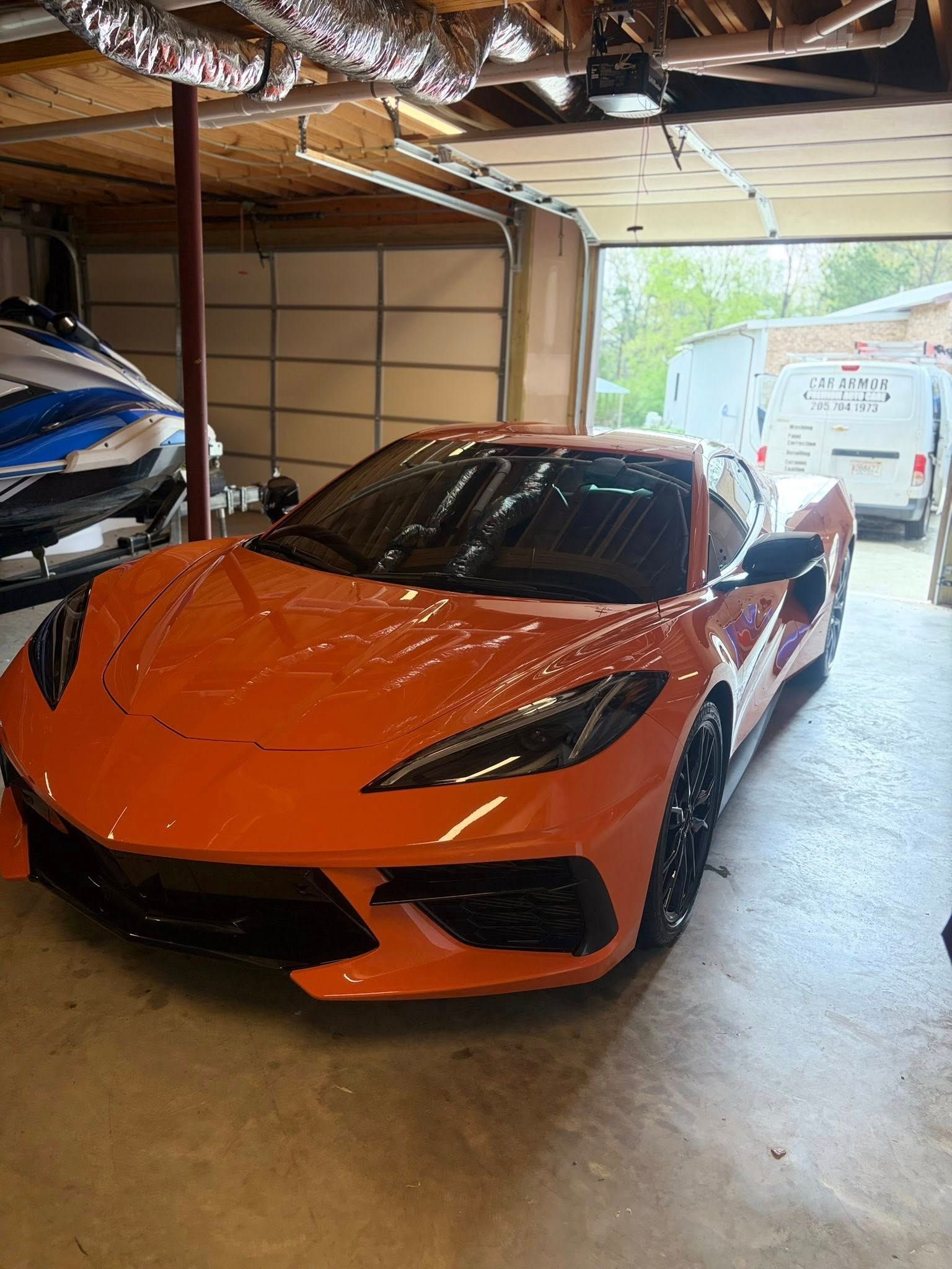 Orange sports car parked inside a garage near an open door with daylight outside