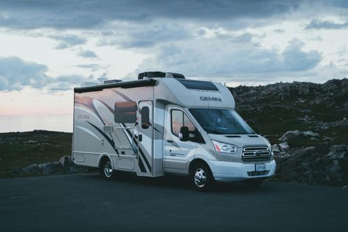 White motorhome parked on a road at dusk under a cloudy sky