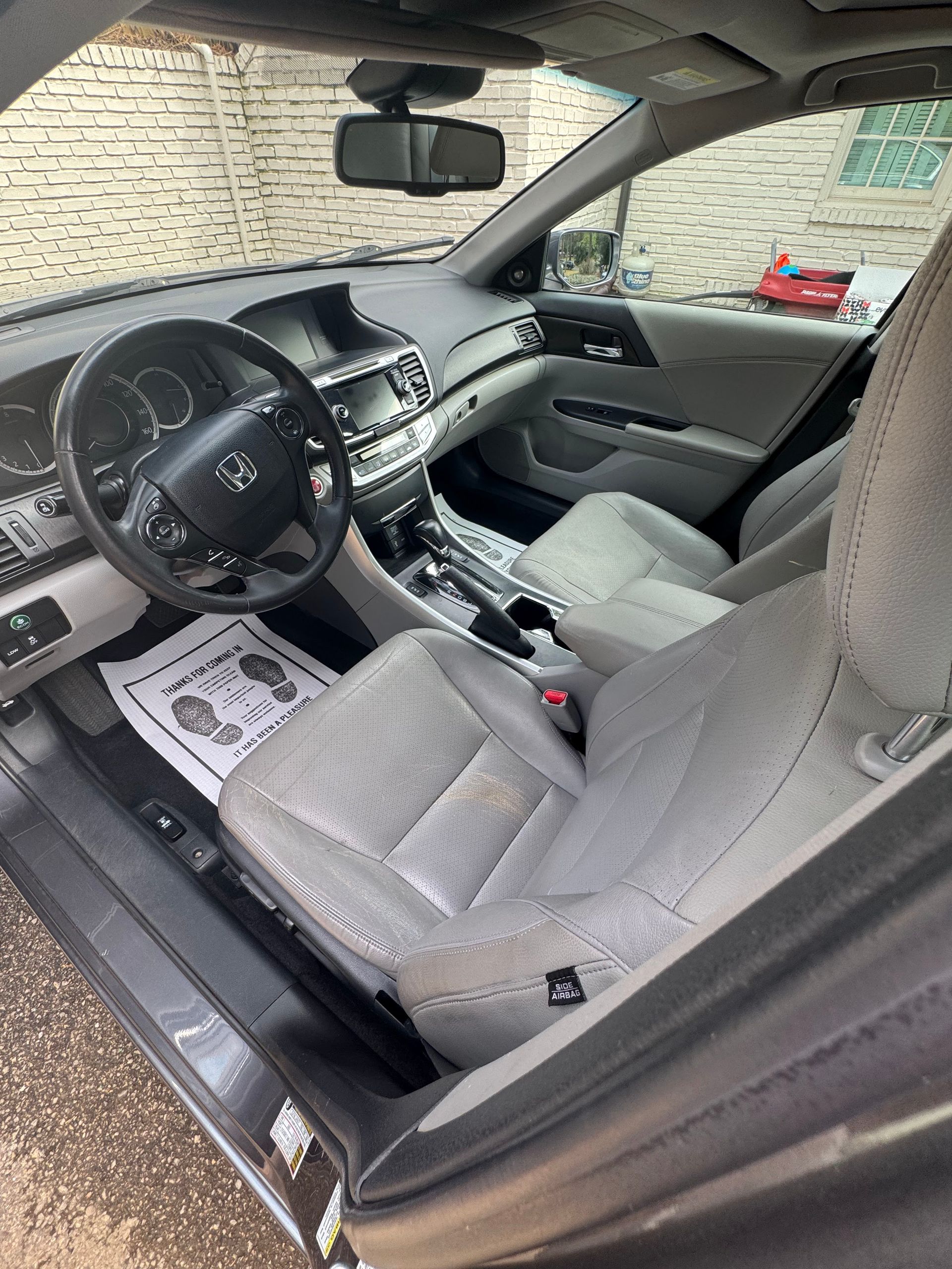 Car interior with gray seats, steering wheel, center console, and sunshade on windshield