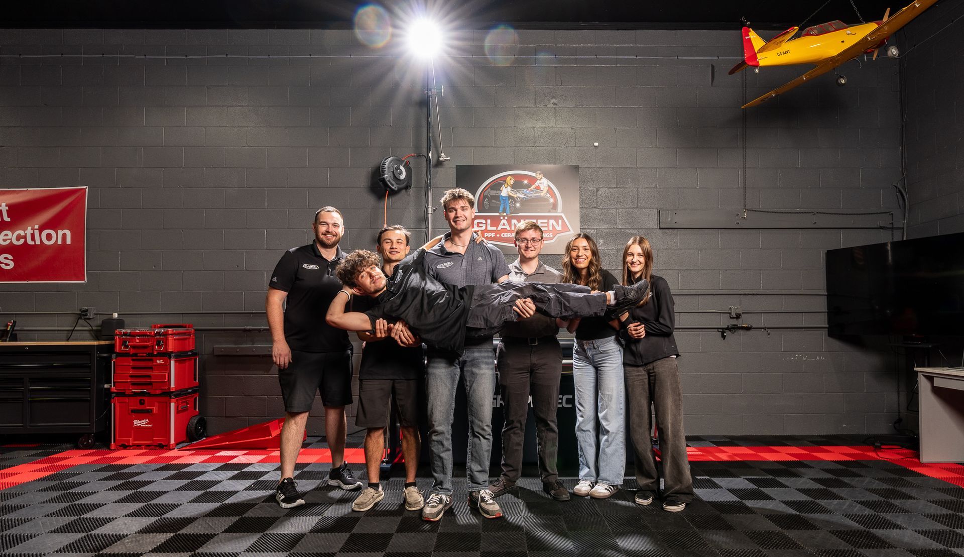 Group of people posing in a dimly lit indoor venue, holding a trophy under bright overhead lights.