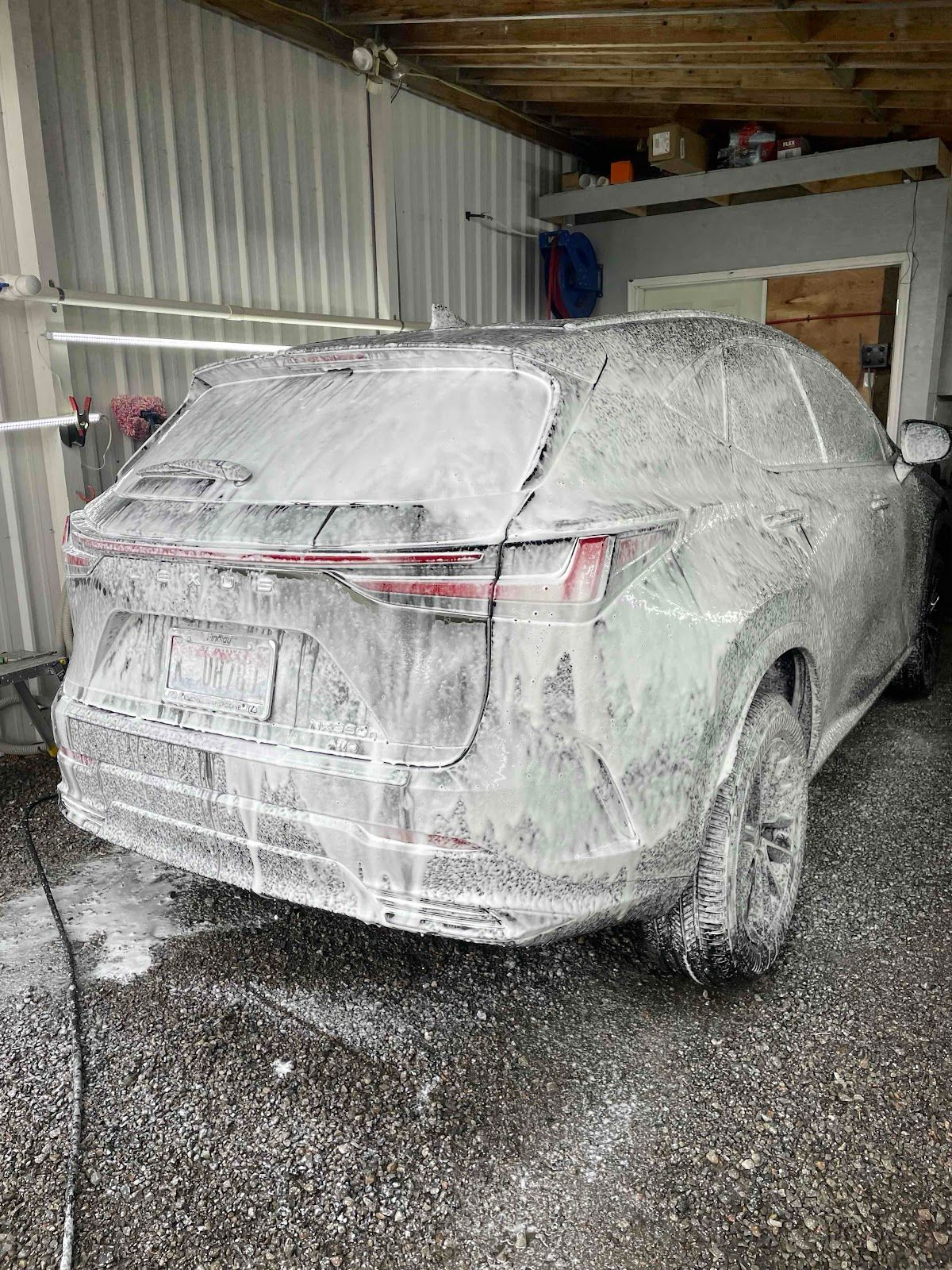A car is covered in foam in a garage.