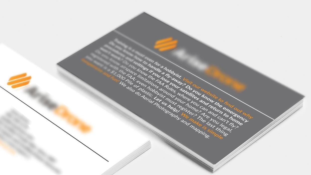 Two blurred business cards, one gray and one white, with orange logo and text, on a white background