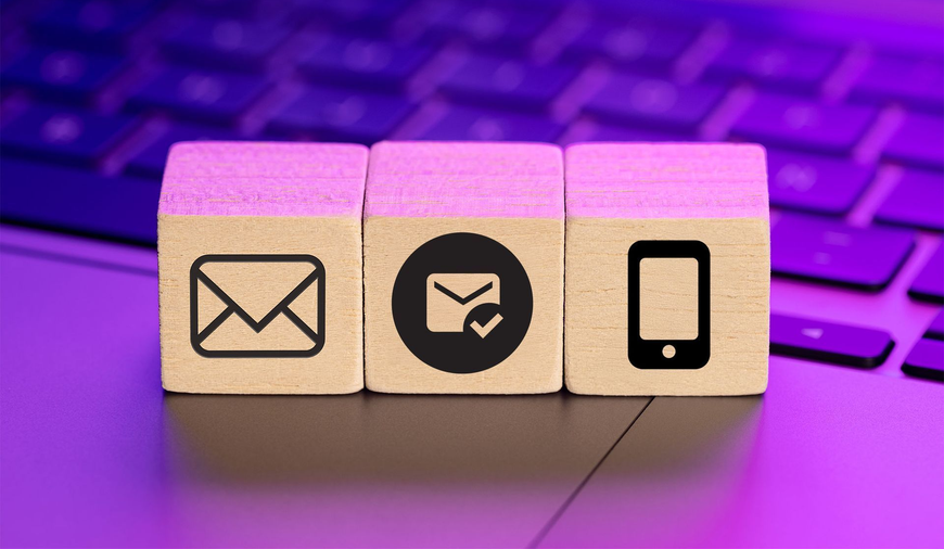 Wooden blocks with email icons and a smartphone on a purple keyboard background