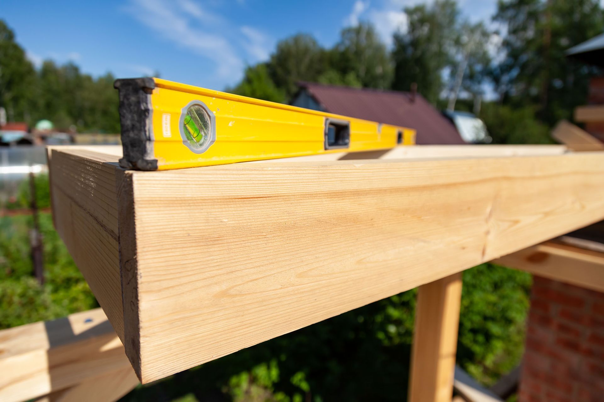 Un niveau jaune est posé sur une poutre en bois.