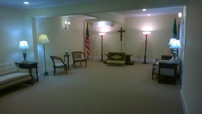 Quiet chapel room with cross, U.S. flag, and chairs along the walls.