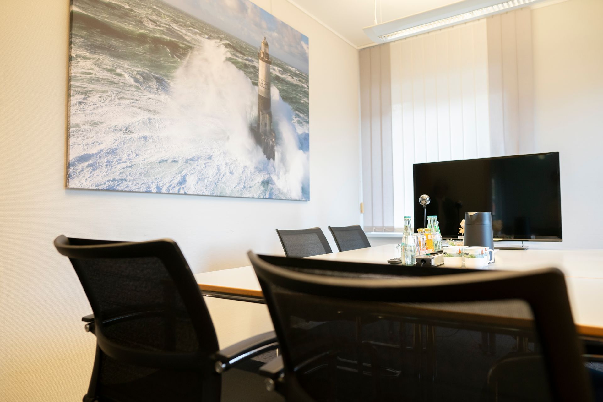 Ein Konferenzraum mit einem Tisch und Stühlen und einem Bild an der Wand.