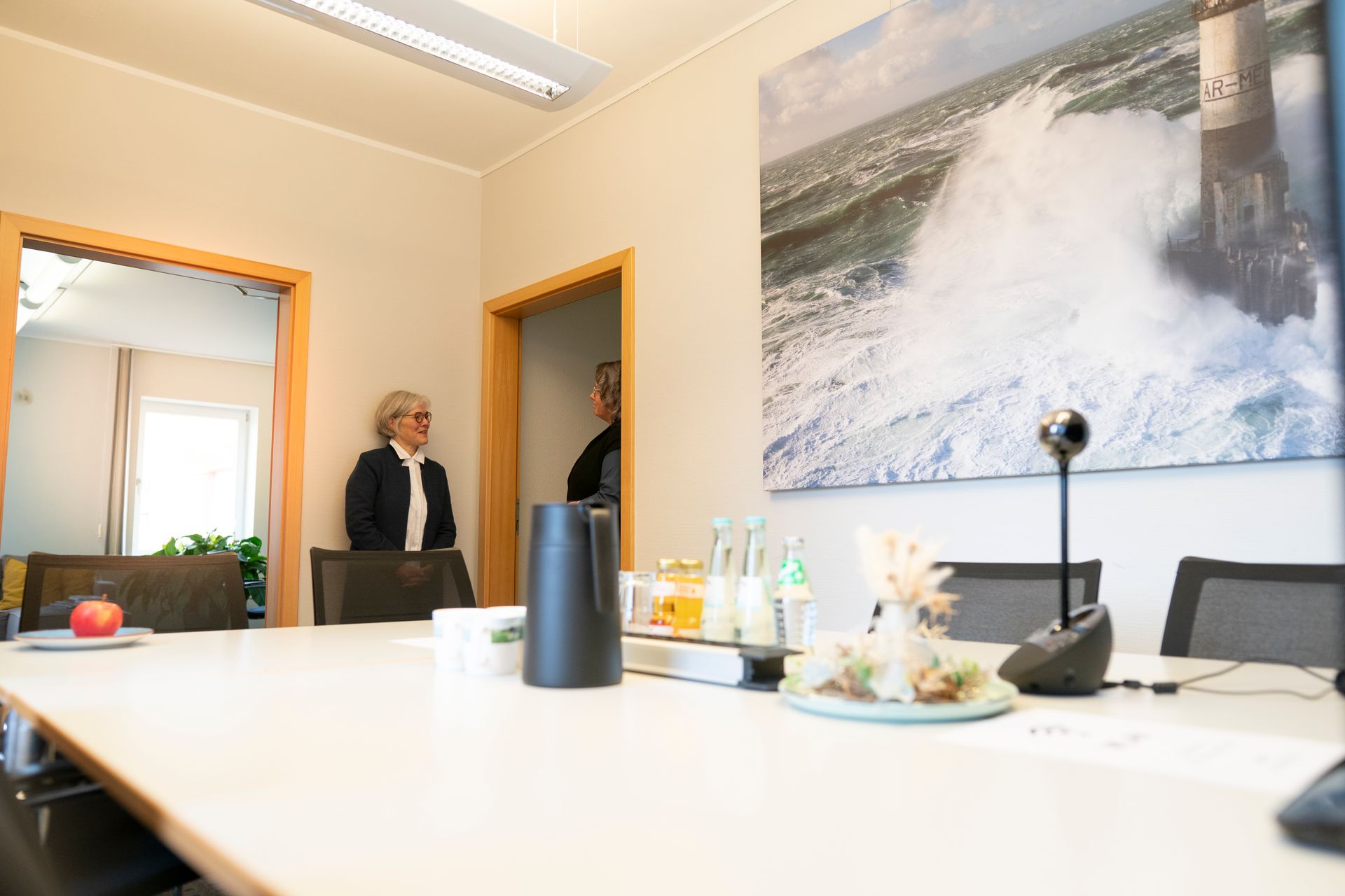 Ein Konferenzraum mit einem langen Tisch und Stühlen und einem Bild an der Wand.