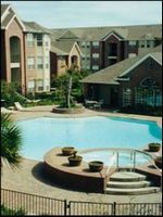 Apartment courtyard with a swimming pool, fountain, and brick buildings surrounding it