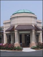 Small domed building entrance with beige columns, green roof, and purple awnings