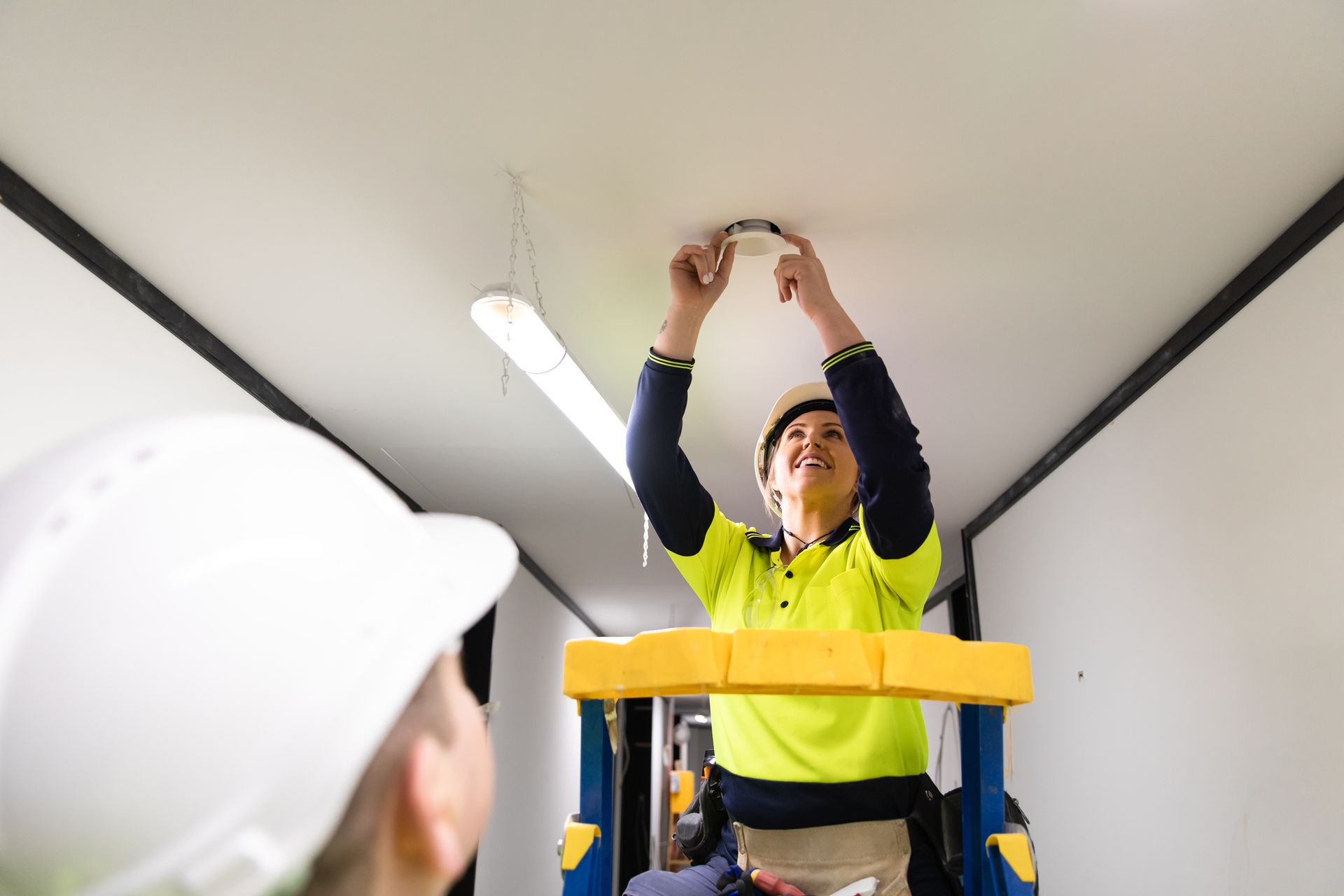 A Woman Is Sitting on a Ladder Fixing a Light on the Ceiling — HBP Electrical LLC — Muscle Shoals, AL
