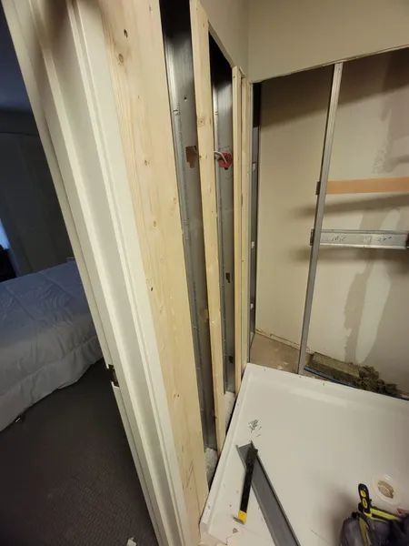 Interior construction of a closet frame. Studs and metal framing are visible near a doorway and a bedroom.