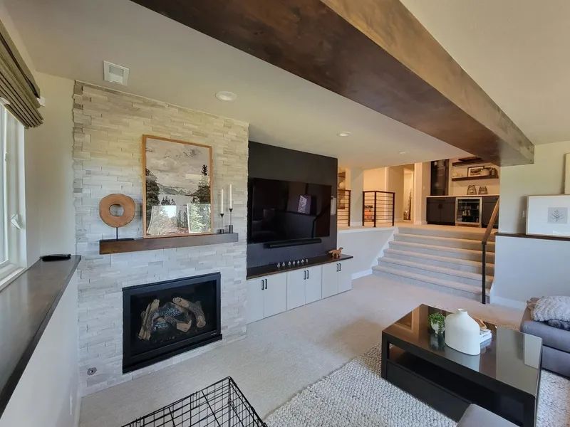Modern living room with a stone fireplace, large TV, and a raised seating area.