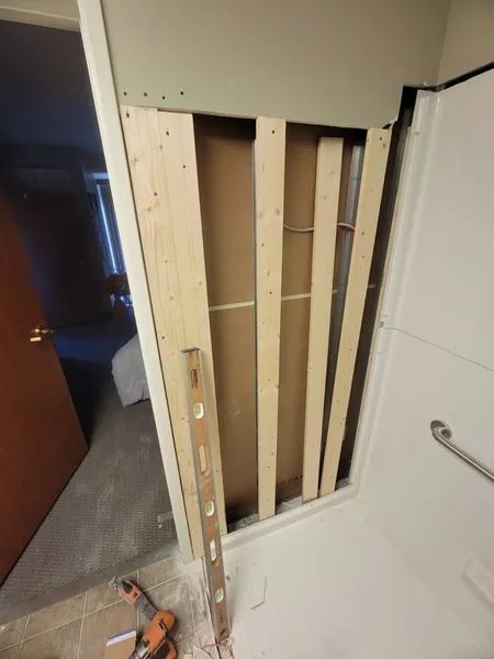 Framing and backing for a wall opening in a bathroom. Level and drill sit in the foreground.