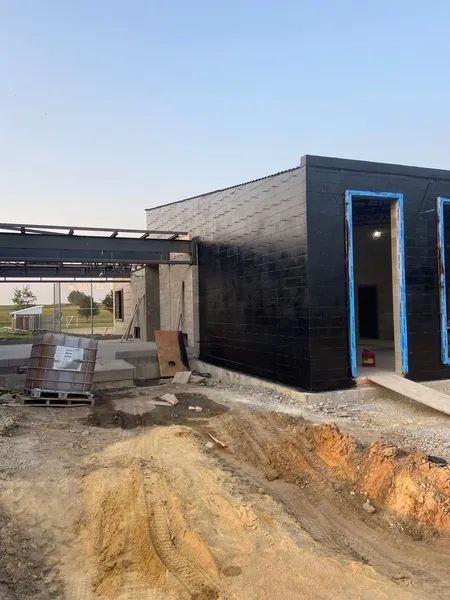 Exterior of a partially constructed black building with blue tape around the door frames.