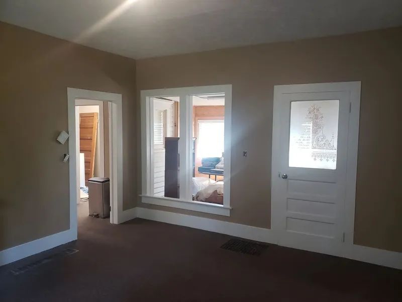 Interior view of a room with tan walls, white trim, and a frosted glass door.