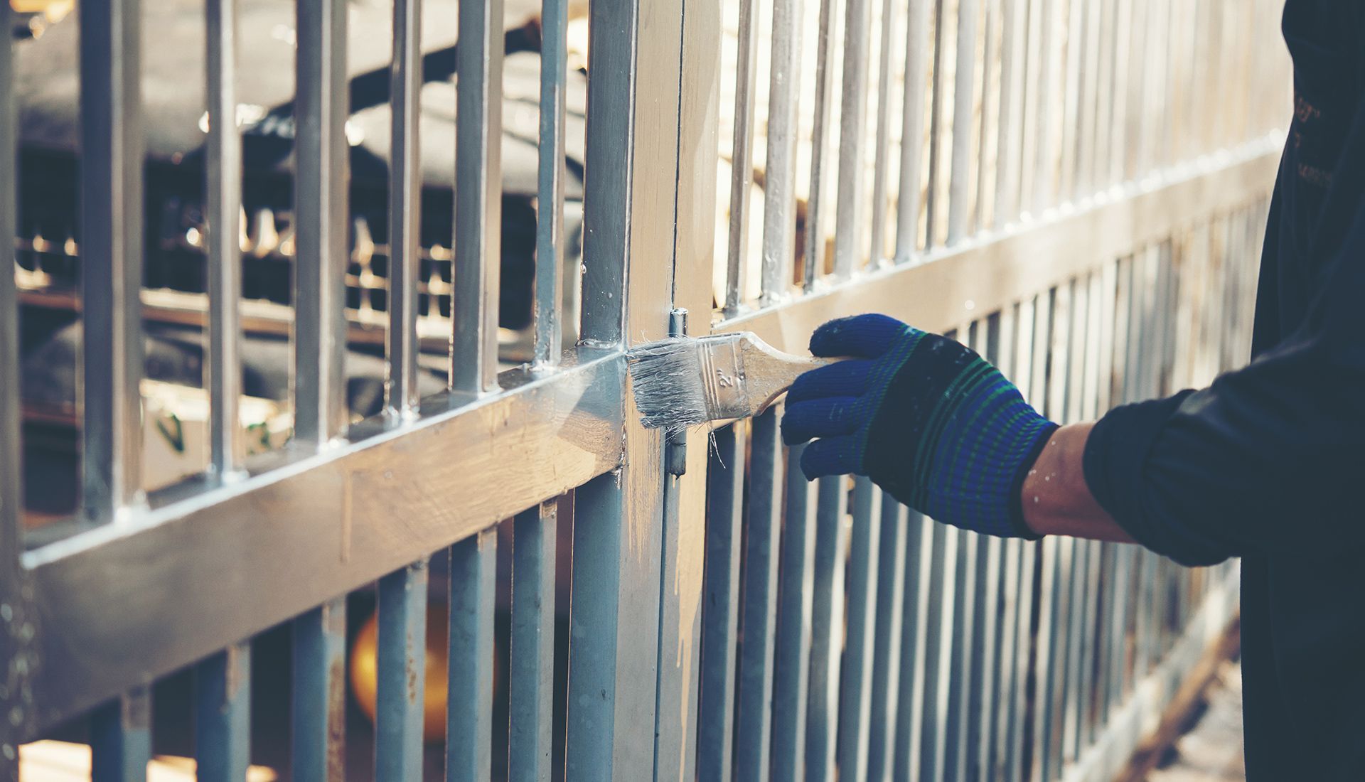 Construction worker in orange hoodie on lift, applying sealant to a concrete block opening.