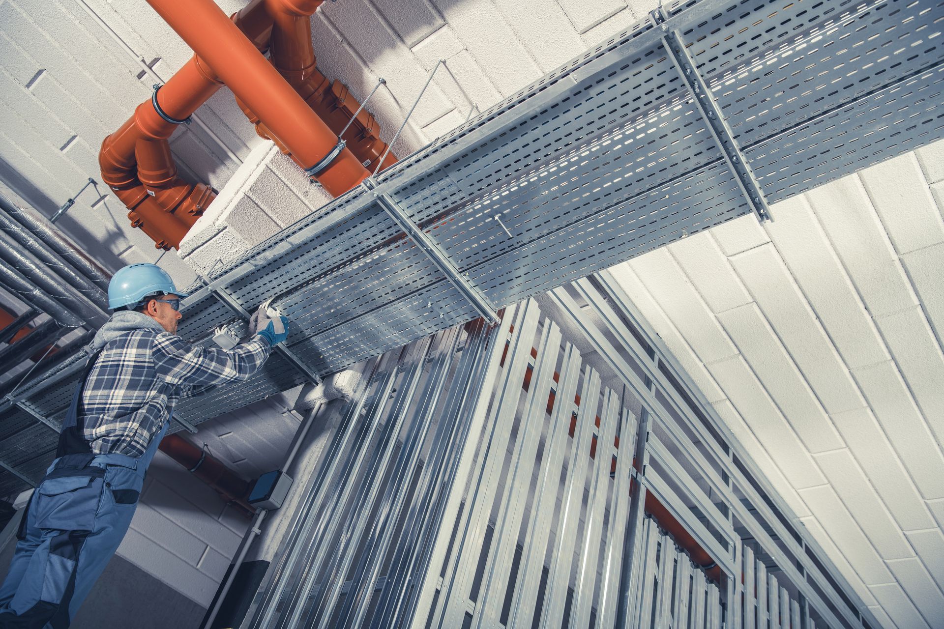 Metal building contractor installing structural steel components inside industrial facility. Metal building contractor installing structural steel components inside industrial facility.