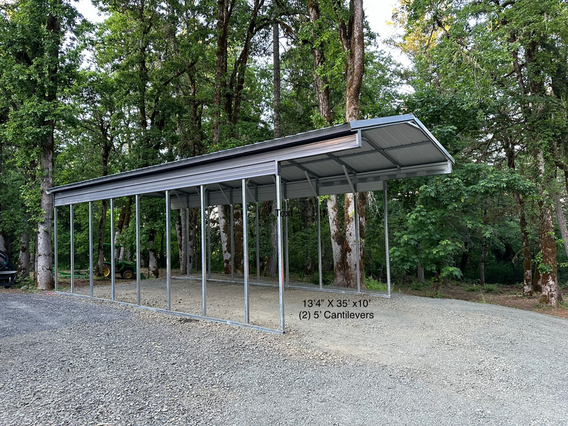 A large metal building with a red roof is sitting on the side of a road.