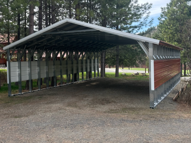 A carport is sitting in the middle of a gravel road.