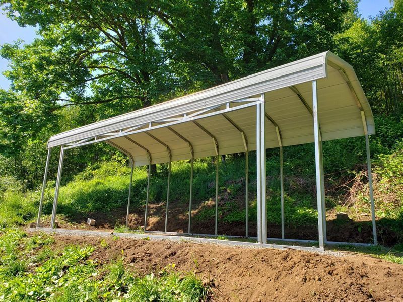 A white carport is sitting on top of a dirt hill.