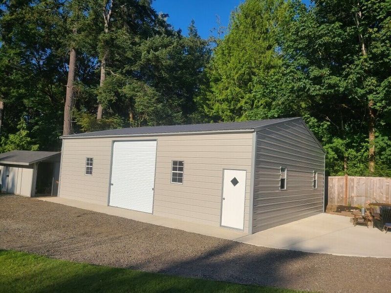 A large metal garage with a white garage door and a white door.