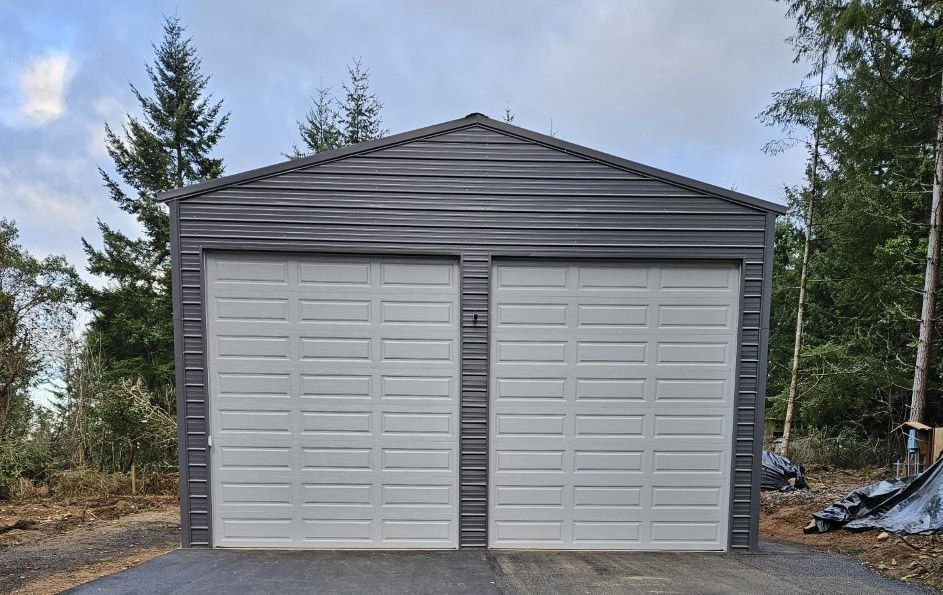 A garage with two garage doors is sitting in the middle of a forest.
