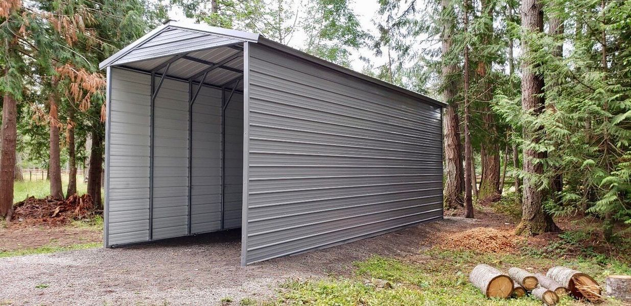 A metal garage is sitting in the middle of a forest.