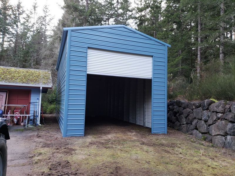 A blue garage with a white door is next to a house.