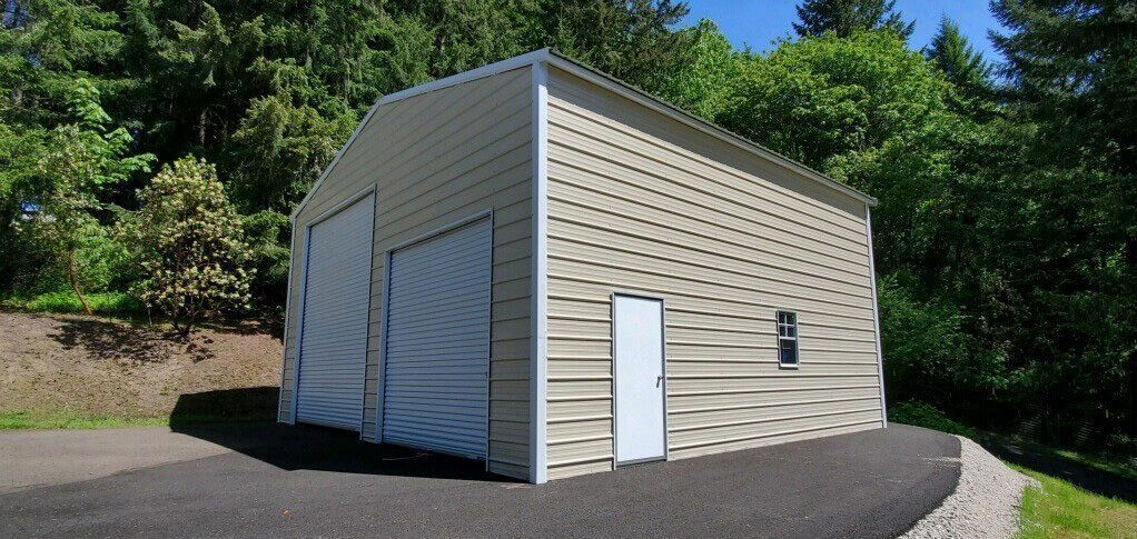 A white garage with a white door is sitting on top of a gravel driveway.