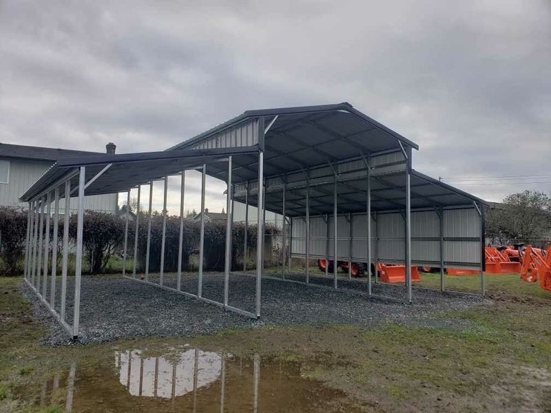 A metal carport is sitting in the middle of a grassy field.